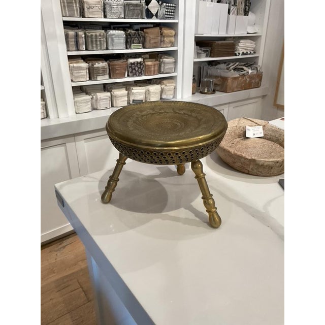 Solid brass low stool with round embossed top and three turned legs. Decorative pierced apron detail beneath the seat....