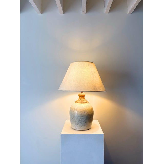 A large ceramic table lamp with a rustic and earthy two tone glaze, dating from the late 20th century. The speckled...