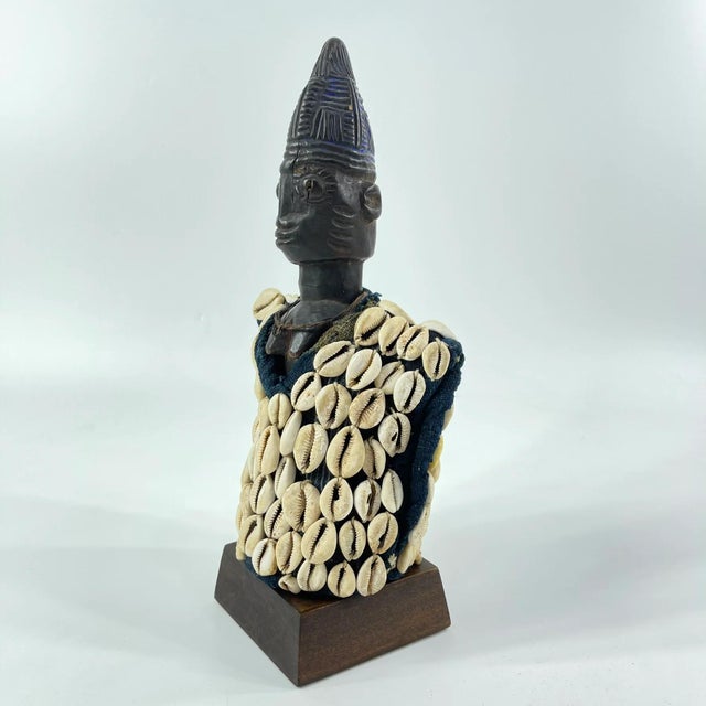 This figure is adorned in a cowrie shell vest, which is removable, and on a custom base. Ibeji figures, carved by the...