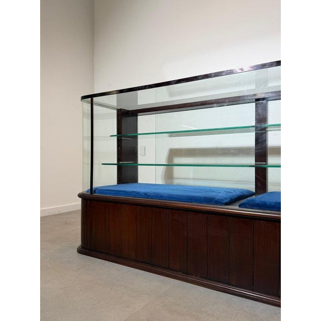 A refined vintage glass display cabinet, crafted in rich mahogany with elegant rounded corners and a timeless retail or...