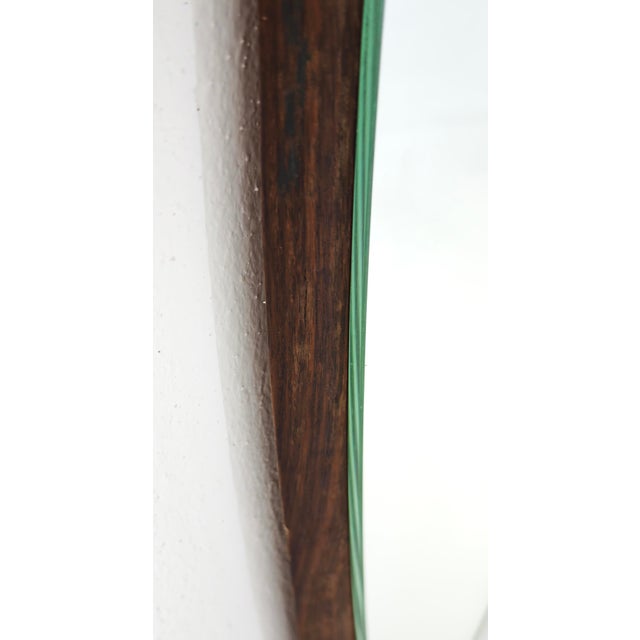 A sculptural mid-century wall mirror, composed of two mirrors shaped like an eye or an elongated leaf, joined by small...