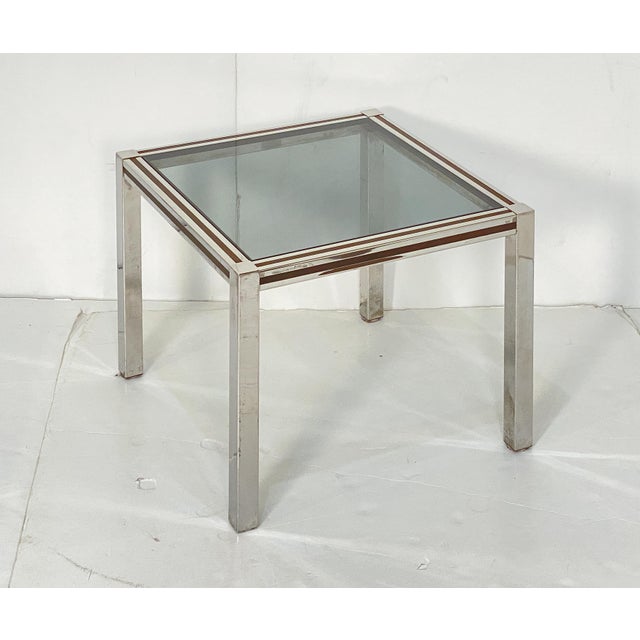 A handsome large French Modern square low side table (or cocktail table) featuring a handsome chrome and brass frame with...