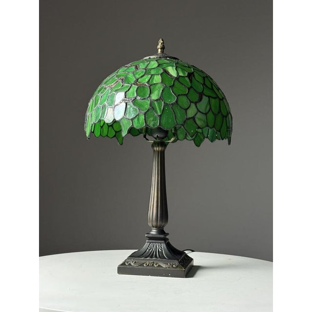 Tiffany style bedside lamp / table lamp. The lamp has a metal base and the shade is made of green glass. Condition is very...
