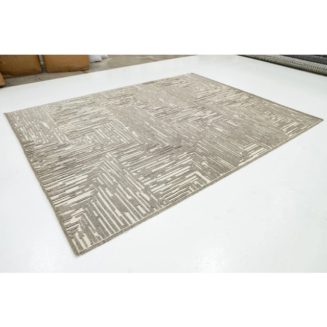 This hand-knotted wool rug showcases a luxurious beige and light brown base with a bold abstract pattern inspired by...