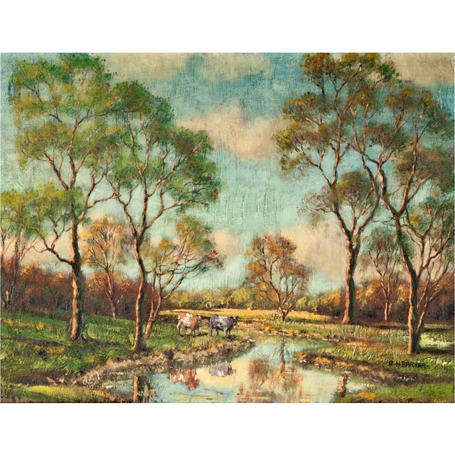 A luminous pastoral oil painting by George H. Barker, depicting two cows beside a reflective pond amid sunlit meadows and...