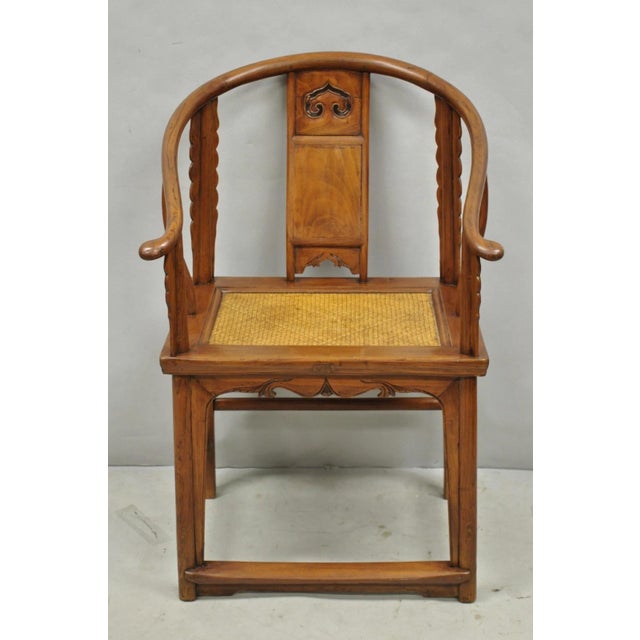 Antique Chinese Elm Hardwood Horseshoe Oriental Huanghuali Lounge Arm Chair with Woven Rattan Seat. Circa Early 20th...