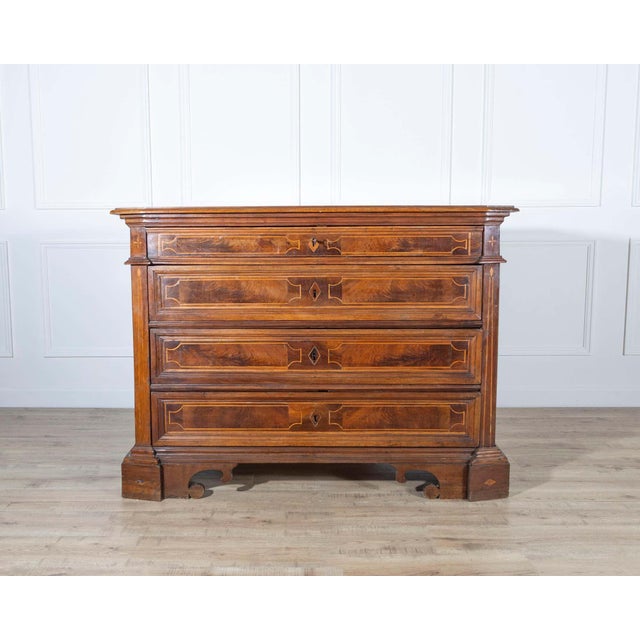 A refined 17th-century chest of drawers from central Italy, crafted in solid walnut and veneered with beautifully figured...