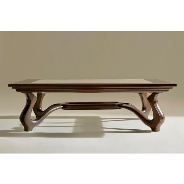 A striking contemporary sculptural coffee or center table featuring a richly stained walnut form with an inset glass top,...