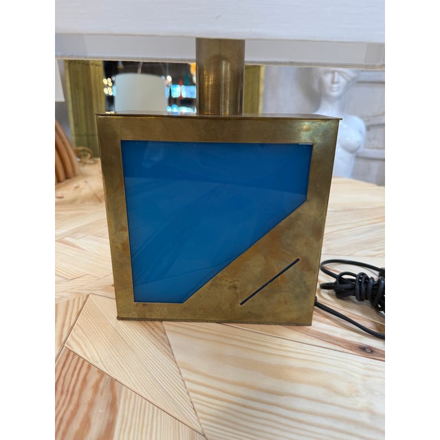Italian table lamp featuring a rectangular brass base with a striking blue lacquered glass panel set into the front face,...