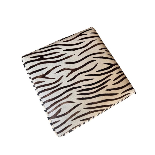 Add a bold, designer touch to any space with this vintage zebra print cowhide ottoman, dating to the early 1990s....