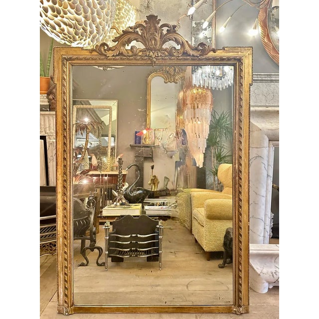 A large antique French gold gilt mirror in the Louis XVI manner. Retaining its original mirror plate with some foxing. The...