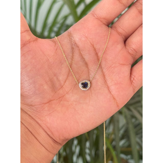 This pendant necklace showcases a 0.35 carat heart-shaped deep blue sapphire, set in 14k yellow gold. the sapphire...