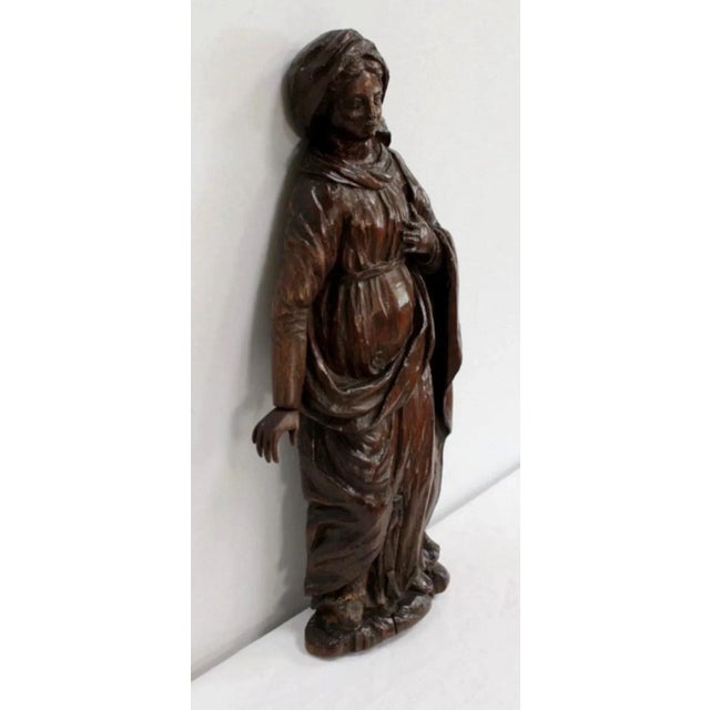 Wall statue in carved wood representing a Saint. This religious subject, with her left hand on her heart, inspires piety....