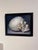 This oil painting presents a meticulously rendered skull, positioned against a dark background that enhances its contours...