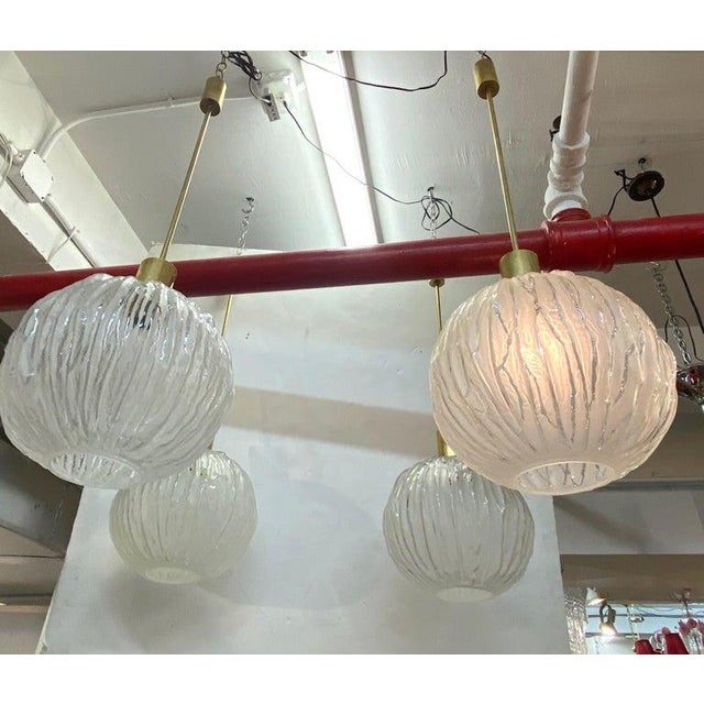 Shown are two of five available Italian 1960s pendant lights by designer Angelo Brotto. Each pendant is comprised of a...