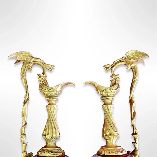 A matching pair of French 19th century painted porcelain ornamental pitchers featuring gilt bronze handles and base.