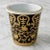 This elegant porcelain wastebasket (or cachepot) features a striking black background with intricate gold scroll and...