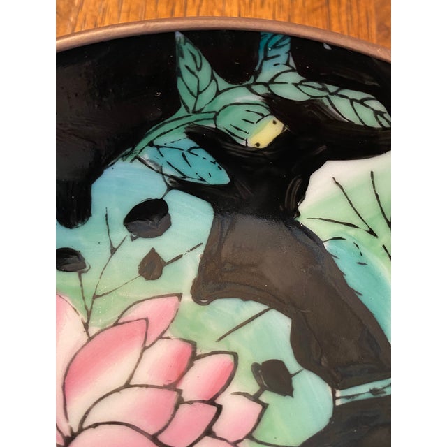 Hand painted porcelain bowl with Lotus flowers in pink and green on a black background. The brass wrap has a hanger. This...