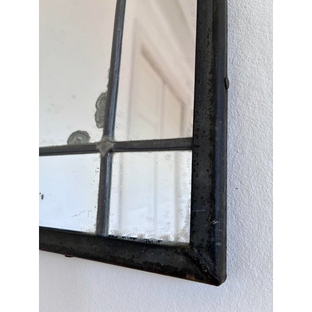Wall mirror with a black-painted wrought iron frame and decorative scrollwork crest in an Art Deco style. The mirror...