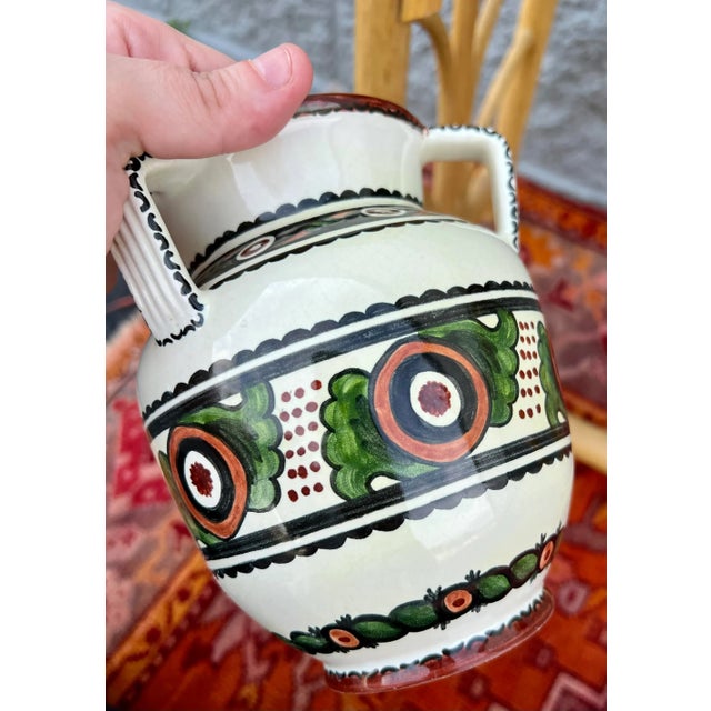 A beautifully painted urn with three handles. Floral motifs are painted in an Art Deco style simple to those of boch...