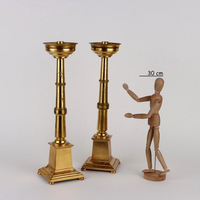 Pair of gilded bronze candlesticks with a square base supported by four circular shaped feet. This piece is attributed to...