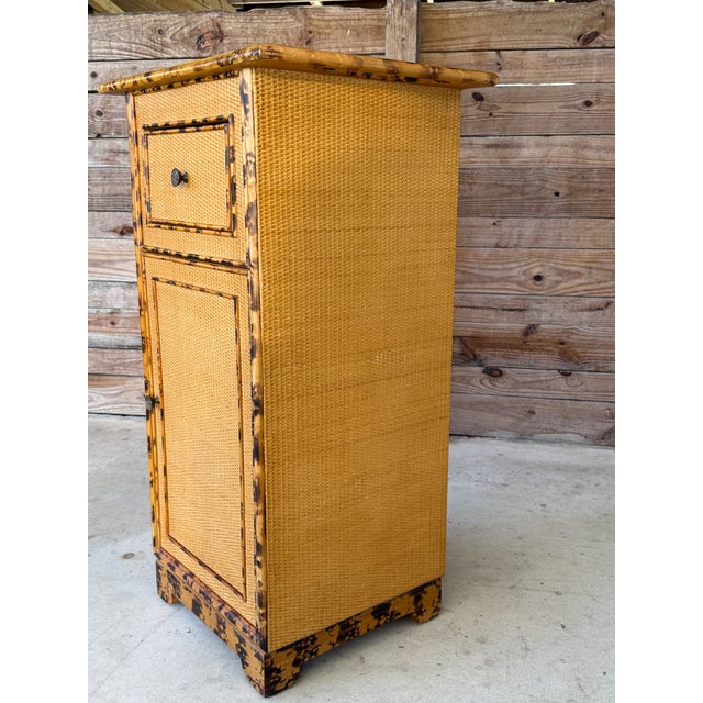 Charming vintage tortoise-finished rattan cabinet, featuring woven rattan panels throughout, a single upper drawer, and a...