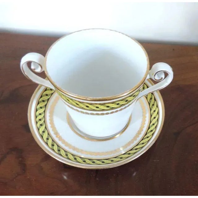 A neoclassical 18th c. English porcelain double handled cup and saucer dish with bold yellow geometric bands enhanced by...