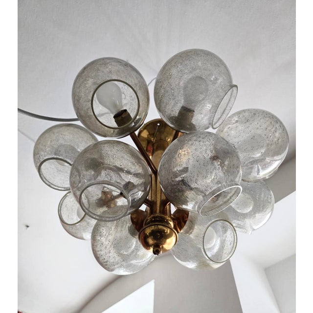 This sculptural chandelier is executed in brass and features ten hand-blown glass globes with a distinctive bubble...