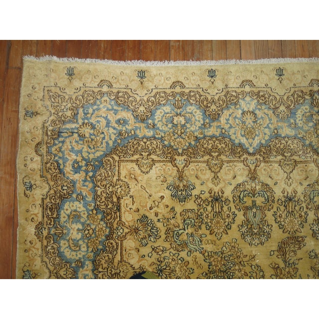 A 20th century room size Persian Kerman rug in beige, light blue, celery green, yellow and brown Measures: 7'5'' x 10'2''.