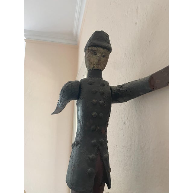 This hand-carved wooden whirligig showcases a detailed Hessian soldier in traditional uniform, capturing a moment of...