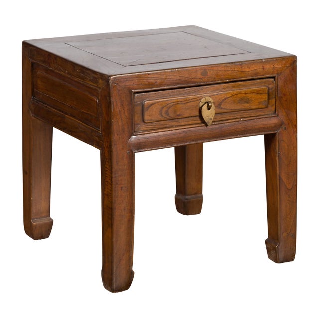 A Chinese Qing Dynasty period elmwood side table from the 19th century, with single drawer, brass hardware and horse hoof...