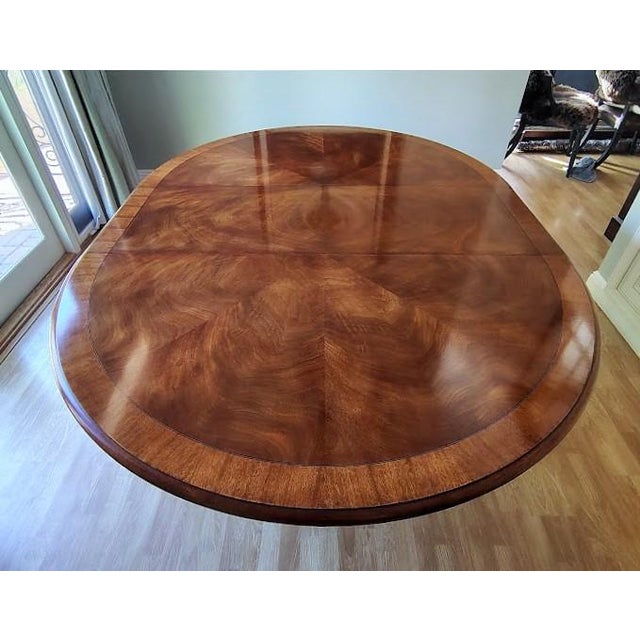 This gorgeous mahogany dining table is made by Henredon. The tabletop has a beautiful sunburst pattern with inlaid bands...