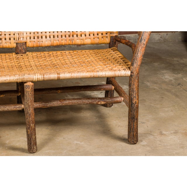 An Old Hickory hoop settee from the mid 20th century with woven rattan back and seat. This mid-20th-century Old Hickory...