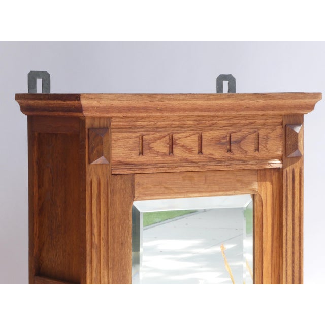 A large antique cabinet made out of wood in Art Deco style with a rectangular beveled mirror in the front. The small chest...