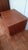 A low, wide teak nightstand in the Danish modern manner, with an open shelf above a full-width drawer. It rolls on hidden...