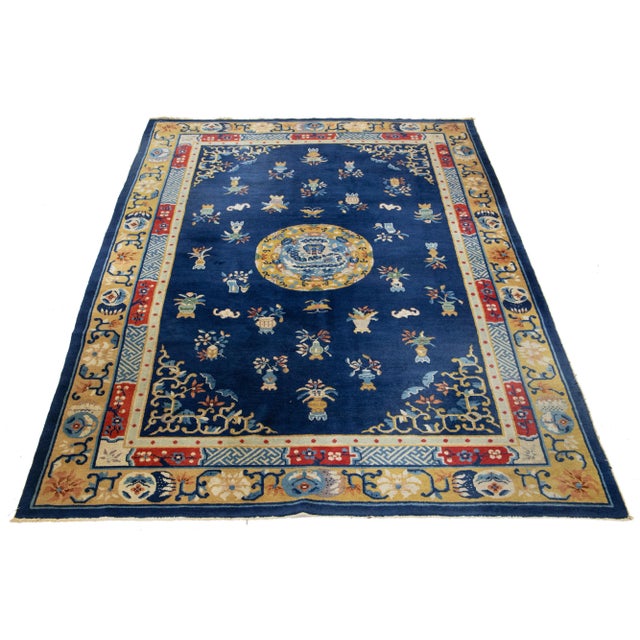 This elegant antique Peking Chinese wool rug features a navy blue field with a decorative border and vibrant color...