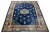 This elegant antique Peking Chinese wool rug features a navy blue field with a decorative border and vibrant color...