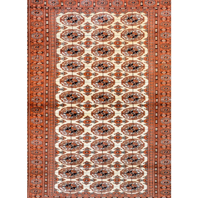 A fantastic vintage Persian Turkoman rug with an all-over field of floral medallions woven in white, cream, brown, and...