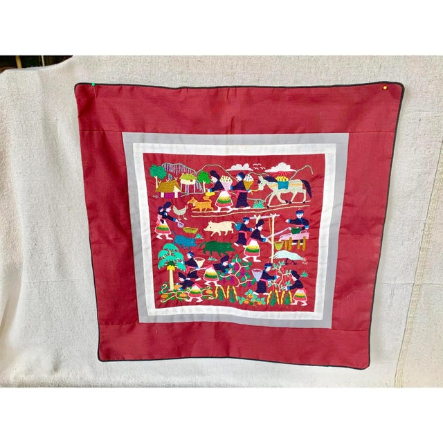 Colorful vintage traditional Hmong hand-embroidered harvest day story cloth pillow cover. Features a rich burgundy red...