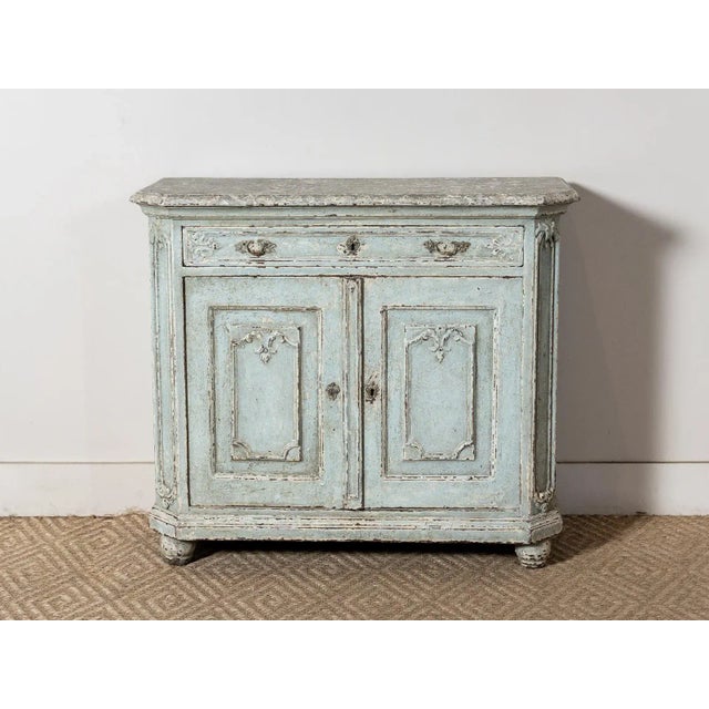 Distressed blue cabinet with decorative wood embellishments and hardware. One drawer and double doors with one interior...