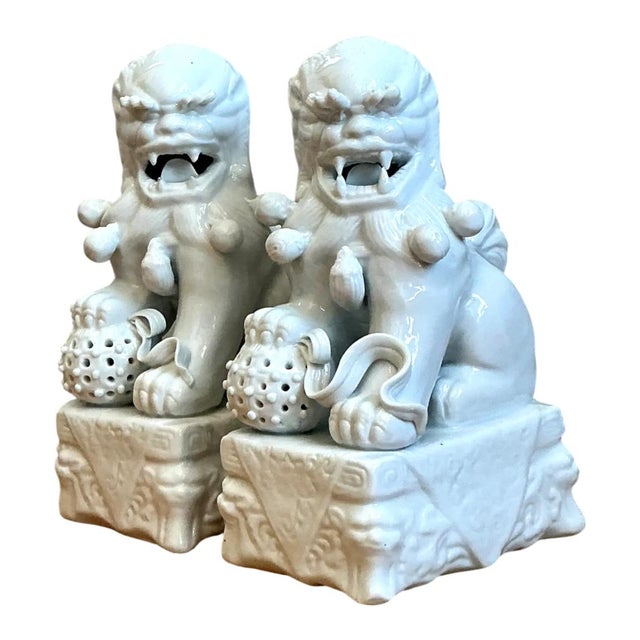 Crafted in the classic Dehua tradition, this pair of vintage Blanc de Chine porcelain foo dogs radiates timeless elegance...