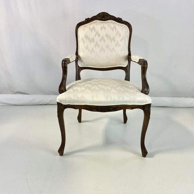 This is a lovely traditional French Provincial style open-armed Bergere Side Chair. The carved wood is walnut with a dark...