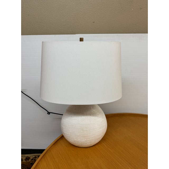 Design Plus Gallery presents the Denali Table Lamp from Hudson Valley Lighting. The textured white base has added brass-...