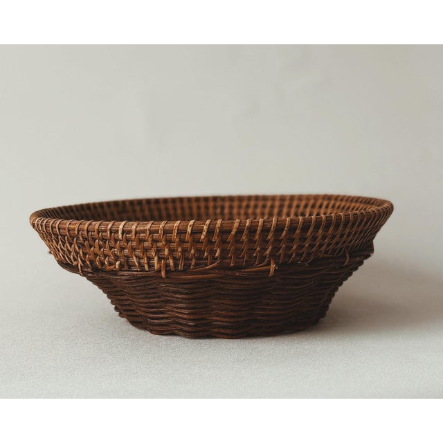 Hand-woven wicker basket with shaped rattan lip rim. Warm honey-brown patina; tight weave throughout. Functional display...