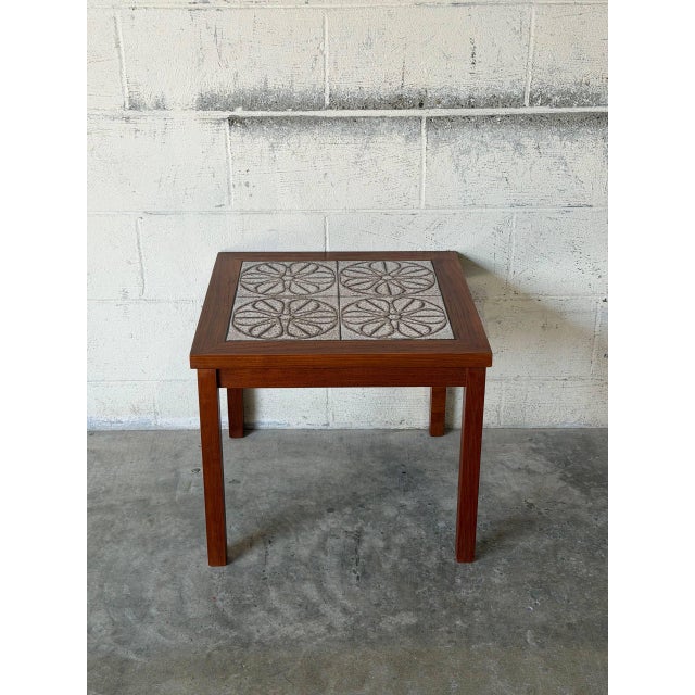 This square side end table features an inset ceramic tile top decorated with a detailed floral motif. Straight wooden legs...