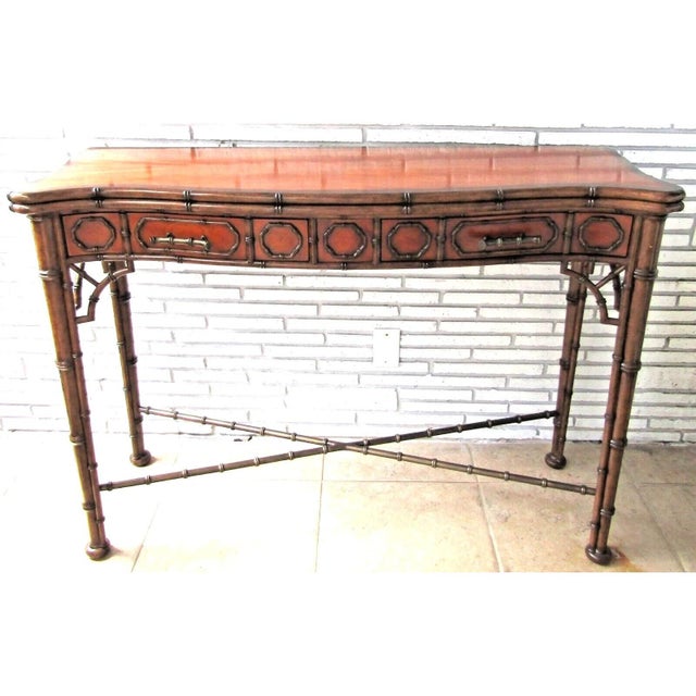 A light faux bamboo carved and mahogany serpentine console table, the crossbanded top above two paneled frieze drawers...