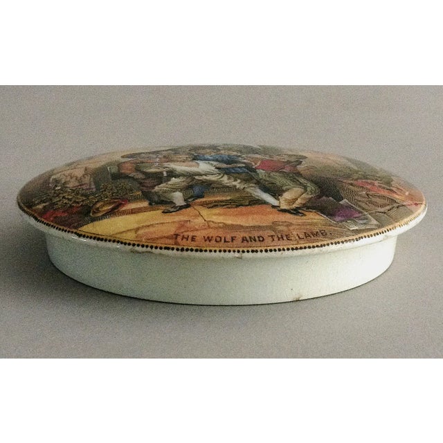 Victorian Staffordshire Prattware multicolored transfer printed pot lid with the title “The Wolf and the Lamb.” It depicts...
