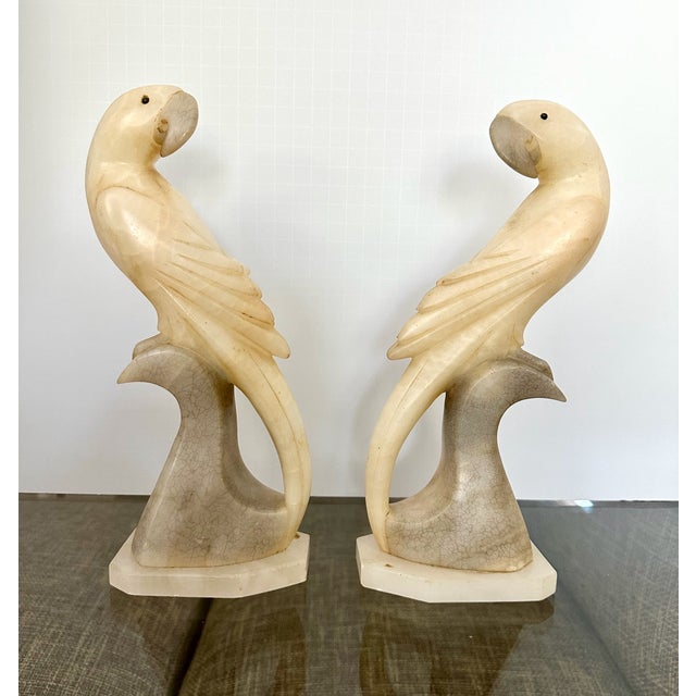 Pair of vintage Italian alabaster facing parrot sculptures, feature a distinct cream and grey veined stone perched on a...