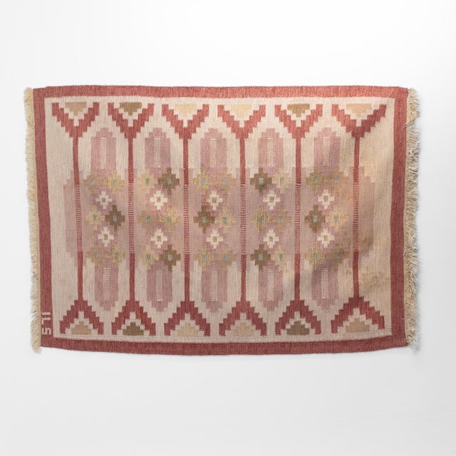 Mid-Century Swedish kilim in tones of red with a cream base. Some staining on one corner. Geometric pattern. Signed ILS....