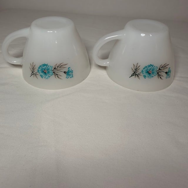 Vintage Fire-King milk glass teacups in the charming Anniversary pattern, featuring a delicate blue cornflower and grey...